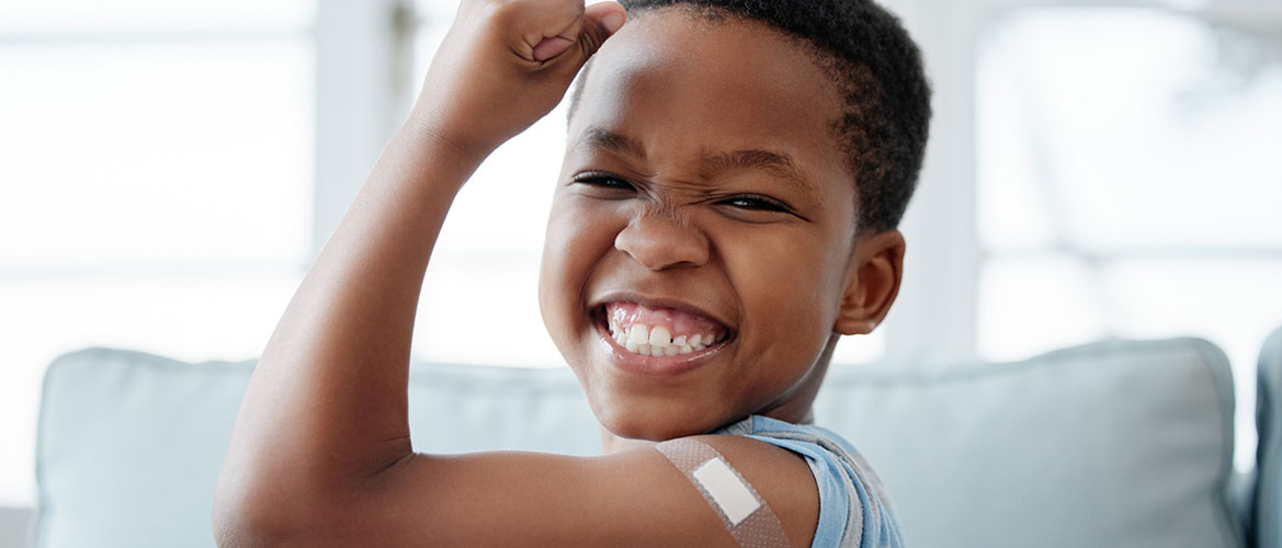 young boy holds up bandaged arm