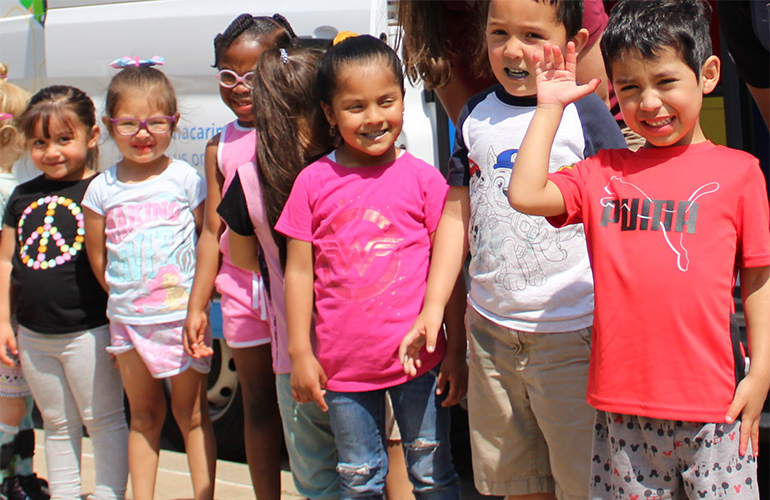 A group of children smile as they pose for a picture