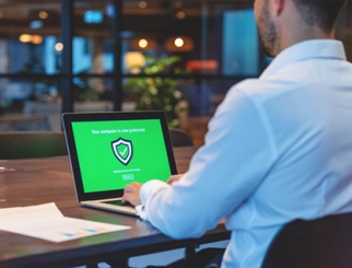 A man viewing a laptop with a security screen.